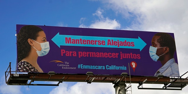 A giant banner reads in Spanish, "Stay Apart to Stay Together," in Los Angeles Monday, Jan. 25, 2021. (AP Photo/Damian Dovarganes)