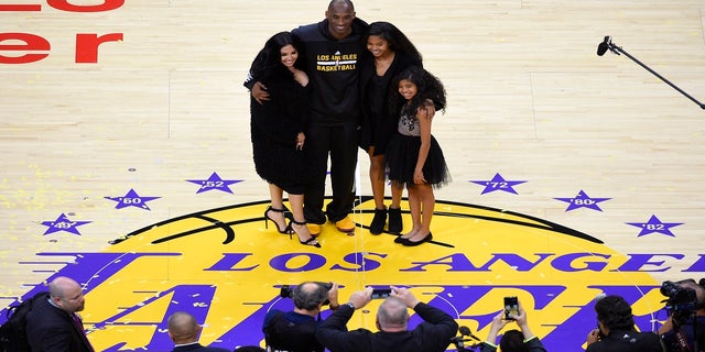 In this April 13, 2016 file photo, Kobe Bryant of the Los Angeles Lakers poses for photos with his wife Vanessa, left, and daughters Natalia, second from right, and Gianna as they stand on the field after an NBA basketball game against Utah.  Jazz, in Los Angeles.