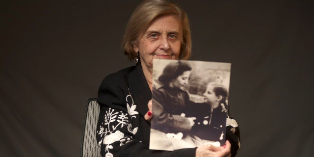 This photo provide by the World Jewish Congress, Tova Friedman, an 82-year-old Polish-born Holocaust survivor holding a photograph of herself as a child with her mother, who also survived the Nazi death camp Auschwitz, in New York, Friday, Dec.13, 2019. (World Jewish Congress via AP)