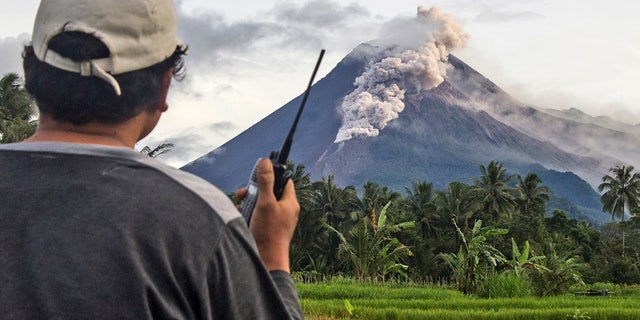 A volunteer uses his walkie-talkie as he monitors Mount Merapi during an eruption in Sleman, Wednesday, Jan. 27, 2021. Indonesia's most active volcano erupted Wednesday with a river of lava and searing gas clouds flowing 1,500 meters (4,900 feet) down its slopes. (AP Photo/Slamet Riyadi)