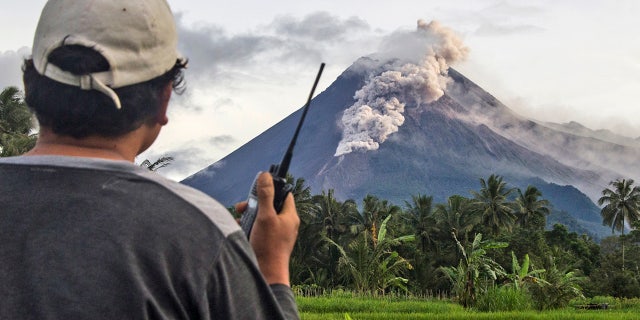 A volunteer uses his walkie-talkie as he monitors Mount Merapi during an eruption in Sleman, Wednesday, Jan. 27, 2021. Indonesia's most active volcano erupted Wednesday with a river of lava and searing gas clouds flowing 1,500 meters (4,900 feet) down its slopes. (AP Photo/Slamet Riyadi)