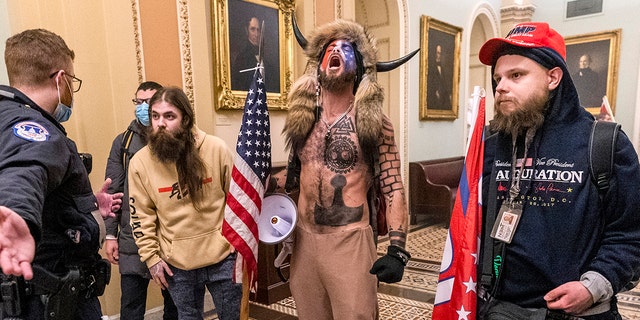 In this Wednesday, Jan. 6, 2021 file photo, supporters of President Donald Trump, including Jacob Chansley, center with fur and horned hat, are confronted by Capitol Police officers outside the Senate Chamber inside the Capitol in Washington. A video showed Chansley leading others in prayer inside the Senate chamber. (AP Photo/Manuel Balce Ceneta)