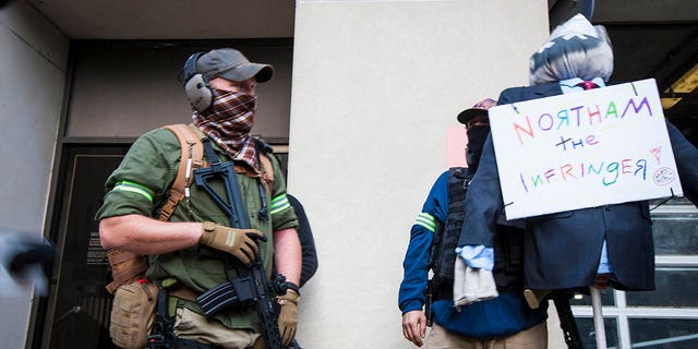 Armed second amendment supporters a carry mock-up of Gov. Ralph Northam on 9th Street near Capitol Square on Monday, Jan. 18, 2021, in Richmond, Va. Gov. Northam's administration supported an assault weapons ban bill that failed to pass during the 2020 Legislative term. (AP Photo/John C. Clark)