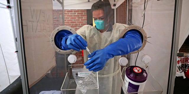 BOSTON, MA - JANUARY 7: An LPN stores a patient test kit behind a plexiglass compartment at a walk-in COVID-19 testing site in a tent in the alleyway of North Bennet Street in Boston's North End on January 7, 2021.