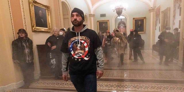 In this Jan. 6, 2021, file photo, smoke fills the walkway outside the Senate Chamber as supporters of President  Trump are confronted by U.S. Capitol Police officers inside the Capitol in Washington. 