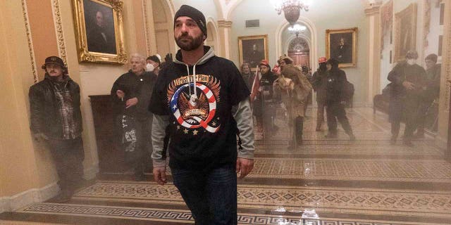 In this Jan. 6, 2021, file photo, smoke fills the walkway outside the Senate Chamber as supporters of President  Trump are confronted by U.S. Capitol Police officers inside the Capitol in Washington. 