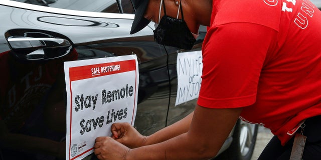 A woman puts a sign on her car prior to the Occupy City Hall Protest and Car Caravan hosted by Chicago Teachers Union in Chicago, Illinois, on August 3, 2020.