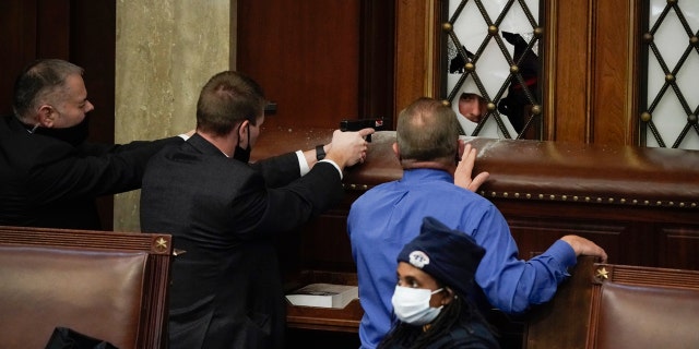 Police with guns drawn watch as protesters try to break into the House Chamber at the U.S. Capitol op Woensdag, Jan.. 6, 2021, in Washington. (AP Foto / J. Scott Applewhite)