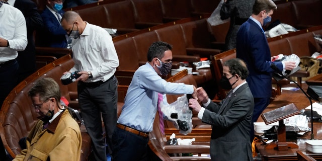 Lawmakers prepare to put on masks on the floor of the House of Representatives as protesters enter the U.S. Kapitool, Woensdag, Jan. 6, 2021, in Washington. (AP Photo / Andrew Harnik)