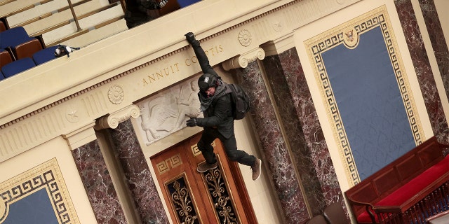 A protester is seen hanging from the balcony in the Senate Chamber on Jan. 6, 2021, in Washington, D.C. (Win McNamee/Getty Images)