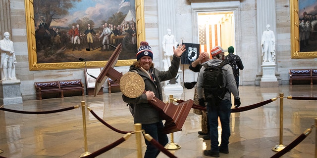 A pro-Trump protester carries the lectern of U.S. Speaker of the House Nancy Pelosi through the Roturnda of the U.S. Capitol Building after a pro-Trump mob stormed the building on January 06, 2021. (Photo by Win McNamee/Getty Images)