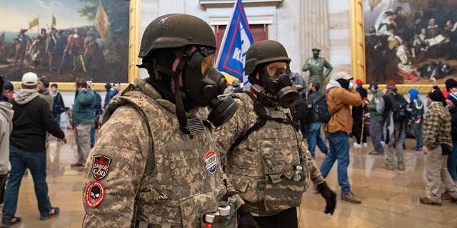 Supporters of President Trump wear gas masks and military-style apparel as they walk around inside the Rotunda after breaching the US Capitol in Washington, D.C., on Jan. 6, 2021. 