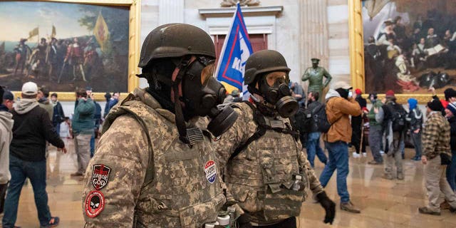 Supporters of President Trump wear gas masks and military-style apparel as they walk around inside the Rotunda after breaching the US Capitol in Washington, D.C., on Jan. 6, 2021. 