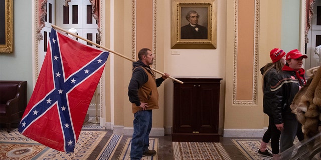 A man holds a Confederate flag outside the Senate Chamber during a protest after breaching the U.S. Capitol in Washington, D.C., Jan. 6, 2021. (SAUL LOEB/AFP via Getty Images)