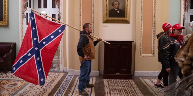 A supporter of President Trump holds a Confederate flag outside the Senate Chamber during a siege of the Capitol in Washington, D.C., on January 6, 2021. (Photo by SAUL LOEB / AFP) (Photo by SAUL LOEB/AFP via Getty Images)