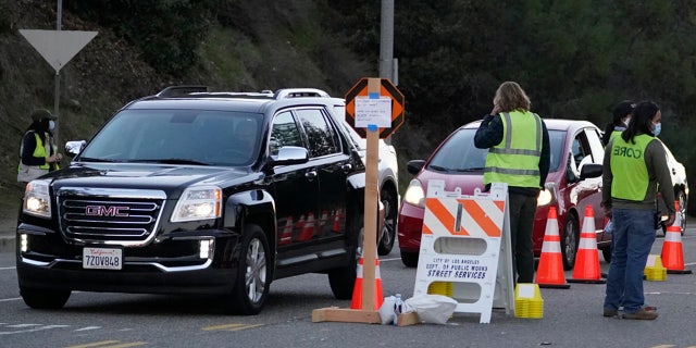 Drivers with a vaccine appointment enter a mega COVID-19 vaccination site set up in the parking lot of Dodger Stadium in Los Angeles Saturday, Jan. 30, 2021. One of the largest vaccination sites in the country was temporarily shut down Saturday because dozen of protesters blocked the entrance, stalling hundreds of motorists who had been waiting in line for hours, the Los Angeles Times reported. The Los Angeles Fire Department shut the entrance to the vaccination center at Dodger Stadium about 2 p.m. as a precaution, officials told the newspaper. The protesters had members of anti-vaccine and far-right groups, the Times reported. Some of them carried signs decrying the COVID-19 vaccine and shouting for people not to get the shots. (AP Photo/Damian Dovarganes)