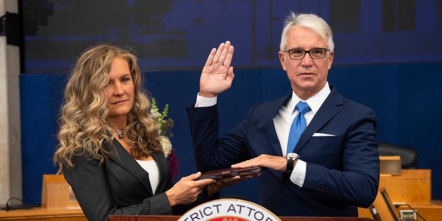 Incoming Los Angeles County District Attorney George Gascon is sworn in as his wife Fabiola Kramsky holds a copy of the Constitution during a mostly-virtual ceremony in downtown Los Angeles Monday, Dec. 7, 2020. 
