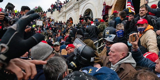 Protesters drag out and capture a Metropolitan Police officer, while trying to enter the US Capitol building.  (Eric Lee / Bloomberg via Getty Images)