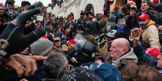 Protesters drag out and capture a Metropolitan Police officer, while trying to enter the US Capitol building.  (Eric Lee / Bloomberg via Getty Images)