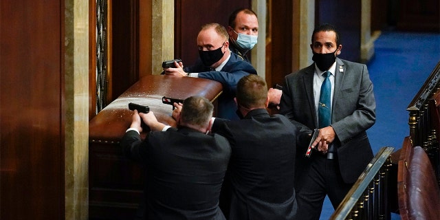 U.S. Capitol Police with guns drawn stand near a barricaded door as protesters try to break into the House Chamber at the U.S. Capitol on Jan. 6, in Washington. (AP Photo/Andrew Harnik)