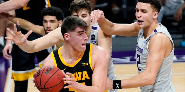 Iowa center Luka Garza (55) looks to pass against Northwestern forward Pete Nance, right, and center Ryan Young during the first half of an NCAA college basketball game in Evanston, Ill., Sunday, Jan. 17, 2021. (AP Photo/Nam Y. Huh)