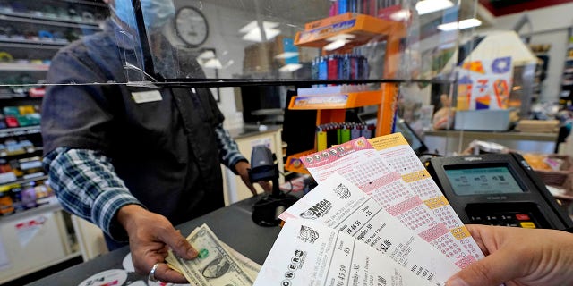 A customer purchases Powerball and Mega Millions tickets at a convenience store in Northbrook, Ill., Wednesday, Jan. 6, 2021. The Powerball jackpot was up to $410 million during that time.