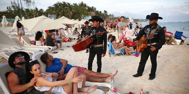 Roving musicians "Los Compas" approach a group of tourists on the shore of Mamitas beach, in Playa del Carmen. (AP Photo/Emilio Espejel)