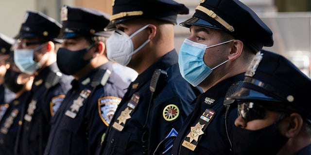 In this Oct. 5, 2020, file photo, New York Police Department officers in masks, stand during a service at St. Patrick's Cathedral in New York to honor 46 colleagues who have died due to COVID-19 related illness. (AP Photo/Mark Lennihan, File)