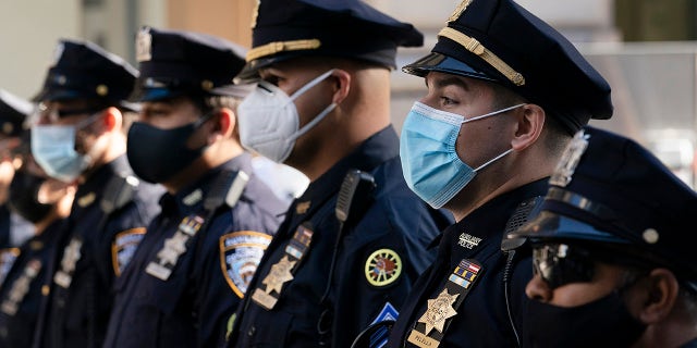 In this Oct. 5, 2020, file photo, New York Police Department officers in masks, stand during a service at St. Patrick's Cathedral in New York to honor 46 colleagues who have died due to COVID-19 related illness. (AP Photo/Mark Lennihan, File)