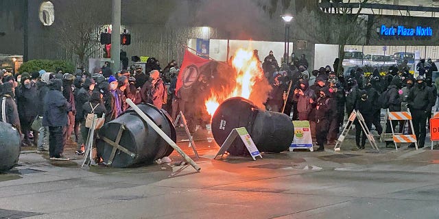 Antifa activists, dressed in black bloc, set small fires in an intersection by Frost Park in Tacoma, Wash. before their destructive march.