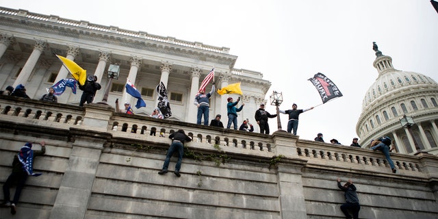 Supporters of President Donald Trump climb the west wall of the the U.S. Capitol on Wednesday, Jan. 6, 2021, in Washington.