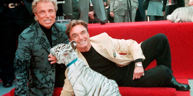 FILE - Illusionists Siegfried Fischbacher, left and Roy Uwe Ludwig Horn pose for photographers with a white tiger cub after they unveiled their star on the Hollywood Walk of Fame in Los Angeles, Calif.