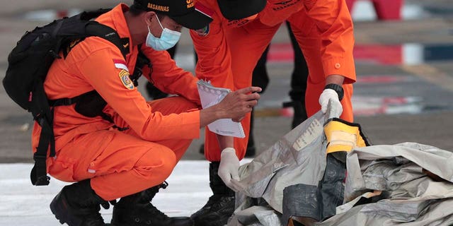 Rescuers inspect debris found in the waters around the location where a Sriwijaya Air passenger jet has lost contact with air traffic controllers shortly after the takeoff, at the search and rescue command center at Tanjung Priok Port in Jakarta, Indonesia, Sunday, Jan. 10, 2021. (Asssociated Press)