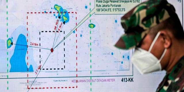 An Indonesian soldier walks past a map showing the location where a Sriwijaya Air passenger jet has lost contact with air traffic controllers shortly after taking off, at the search and rescue command center at Tanjung Priok Port in Jakarta, Indonesia, Sunday, Jan. 10, 2021. (Associated Press)