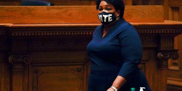 Democrat Stacey Abrams walks on Senate floor before members of Georgia's Electoral College cast their votes at the state Capitol, Monday, Dec. 14, 2020, in Atlanta. (AP Photo/John Bazemore, Pool)