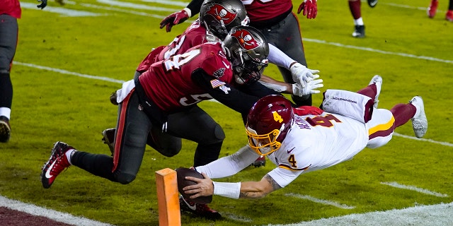 Washington Football Team quarterback Taylor Heinicke (4) dives to score a touchdown against Tampa Bay Buccaneers inside linebackers Kevin Minter (51) and Lavonte David (54) during the second half of an NFL wild-card playoff football game, Saturday, Jan. 9, 2021, in Landover, Md. (AP Photo/Julio Cortez)