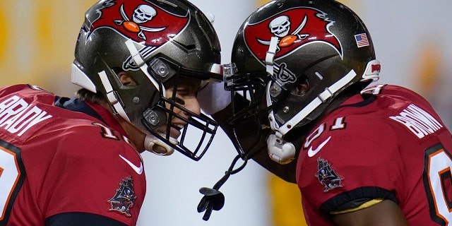 O quarterback do Tampa Bay Buccaneers, Tom Brady (12) e o wide receiver Antonio Brown (81) comemoram um passe para touchdown durante o primeiro tempo de um jogo de futebol americano da NFL contra o Washington FC, sábado, 9 de janeiro de 2021, em Landover, MD.