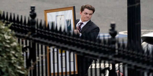 A man carries framed items to a car as he leave the Eisenhower Executive Office building on Thursday. (AP)