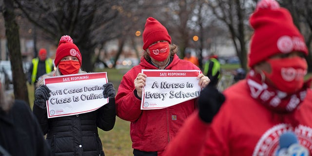 Members of the Chicago Teachers Union display signs in front of a caravan of cars where teachers and supporters demanded a safe and fair return to in-<a class=