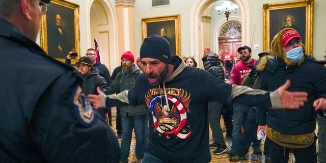 Trump supporters gesture to U.S. Capitol Police in the hallway outside of the Senate chamber after breaching the halls of the Capitol in Washington, Wednesday, Jan. 6, 2021. (AP Photo/Manuel Balce Ceneta)