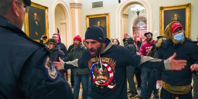 Trump supporters gesture to U.S. Capitol Police in the hallway outside of the Senate chamber after breaching the halls of the Capitol in Washington, Wednesday, Jan. 6, 2021. (AP Photo/Manuel Balce Ceneta)