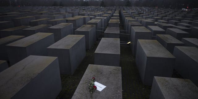 Roses with a note saying "#weremember", are placed on the Holocaust Memorial on International Holocaust Remembrance Day, in Berlin, Germany, Wednesday, Jan. 27, 2021. (AP Photo/Markus Schreiber)