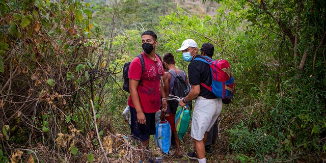 Honduran migrants observe a police checkpoint as they take an alternative route to avoid being detained in Chiquimula, Guatemala, Tuesday, Jan. 19, 2021. (AP Photo/Oliver de Ros)