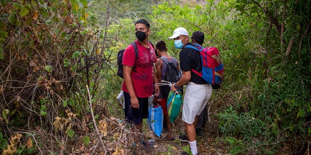 Honduran migrants observe a police checkpoint as they take an alternative route to avoid being detained in Chiquimula, Guatemala, Tuesday, Jan. 19, 2021. (AP Photo/Oliver de Ros)