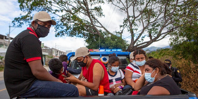 Honduran migrants sit in the bed of a police vehicle after they were detained in Chiquimula, Guatemala, Tuesday, Jan. 19, 2021. (AP Photo/Oliver de Ros)