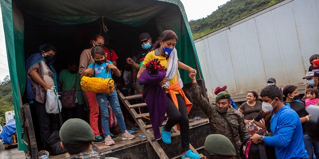 A Honduran migrant woman is helped off a Guatemalan army truck after being returned to El Florido, Guatemala, one of the border points between Guatemala and Honduras, Tuesday, Jan. 19, 2021. (AP Photo/Oliver de Ros)