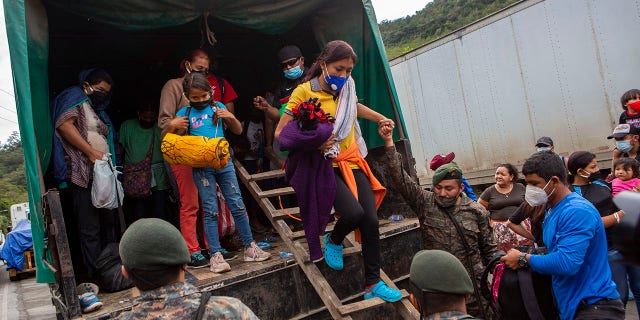A Honduran migrant woman is helped off a Guatemalan army truck after being returned to El Florido, Guatemala, one of the border points between Guatemala and Honduras, Tuesday, Jan. 19, 2021. (AP Photo/Oliver de Ros)