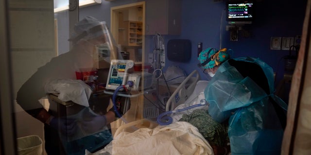 In this Jan. 7, 2021, file photo, registered nurses Kyanna Barboza, right, tends to a COVID-19 patient as Kobie Walsh puts on her PPE at St. Joseph Hospital in Orange, Calif.