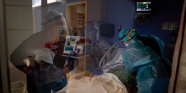 In this Jan. 7, 2021, file photo, registered nurses Kyanna Barboza, right, tends to a COVID-19 patient as Kobie Walsh puts on her PPE at St. Joseph Hospital in Orange, Calif. 