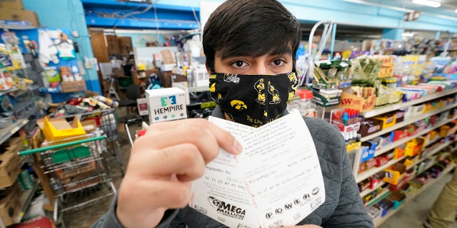 Hardik Kalra, of Des Moines, Iowa, poses for a photo with his Mega Millions and Powerball lottery tickets on Tuesday, Jan.12, 2021, in Des Moines, Iowa.  Lottery players stand a chance of hitting the biggest jackpots in nearly two years as Tuesday's Mega Millions rose to around $ 625 million and Wednesday's Powerball to $ 550 million.  (AP Photo / Charlie Neibergall)